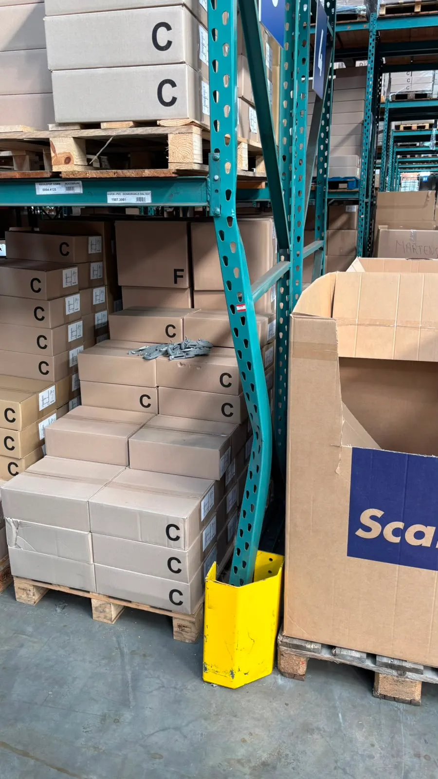 Ernstig verbogen staander van een palletstelling naast een verschoven aanrijdbeveiliging